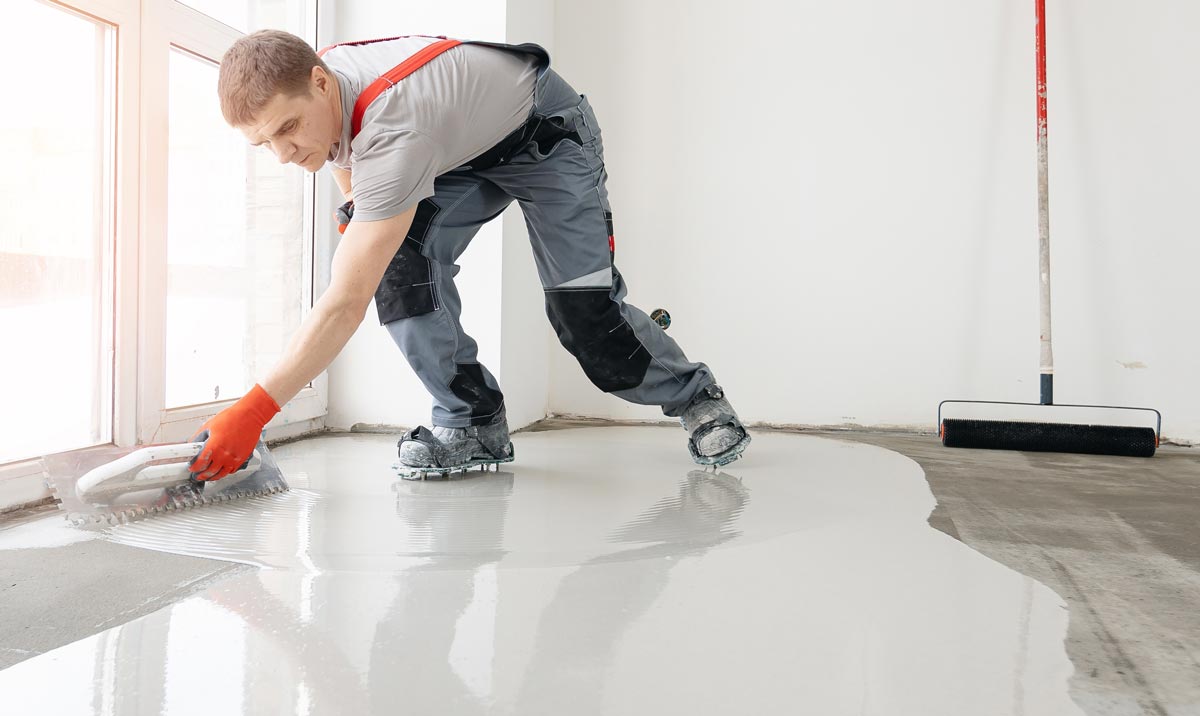 Man applying surface levelling compound to a concrete floor